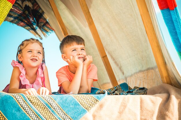 写真 一緒に遊んでいる子供たちのキャンプの兄と妹は、屋外で楽しんでいるテントで遊んでいる幸せな子供たちの家族...