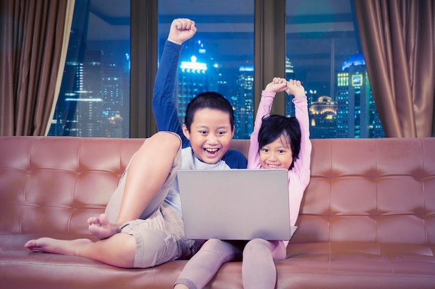 Kids cheering while operating a laptop at night