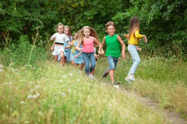 子供たち、緑の牧草地、森を走る子供たち