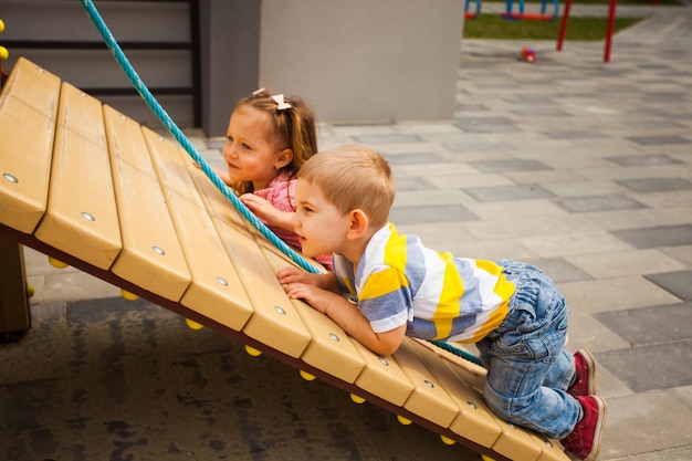 Kids climbing the rope on modern playground in summer time