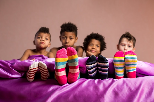 Kids in colorful socks sitting. Boys in socks on bed. One company four emotions. Each of them feels different.