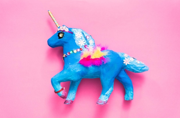 kids craft. painted blue and decorated with jewels and feathers paper mache unicorn.
