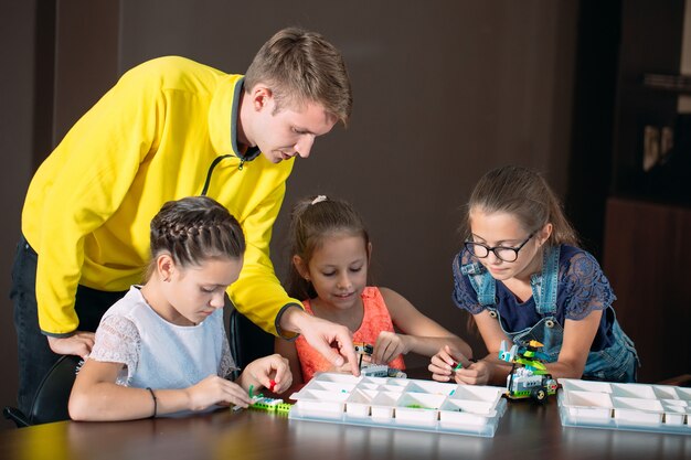 Kids creating robots with teacher. Early development, diy, innovation, modern technology .