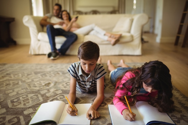 Kids doing homework while lying on rug