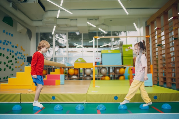 Kids doing massage hedgehog for foot legs exercises in gym at kindergarten or elementary school children sport and fitness concept