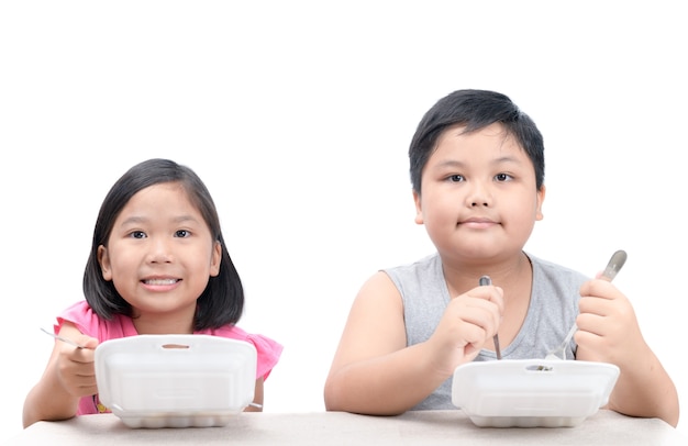 Kids che mangiano riso fritto in scatola della schiuma isolata