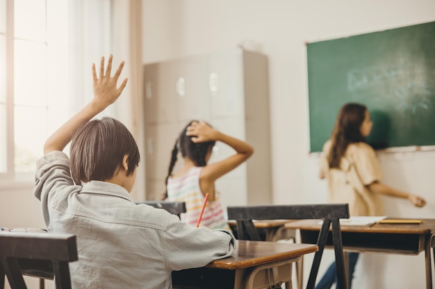 学校の教室での子供の教育 先生に質問するための男の子の手の上昇 問題