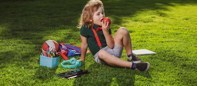 Educazione dei bambini scolaro con materiale scolastico in giardino bellissimo ragazzo è felice di apprendimento