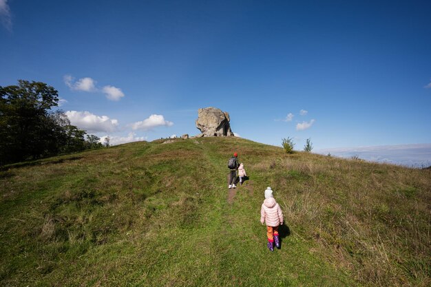 Kids exploring nature Children wear backpack hiking near big stone in hill Pidkamin Ukraine