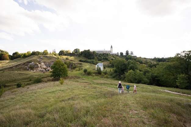 Kids exploring nature Children wear backpack hiking with mother in hill Pidkamin Ukraine