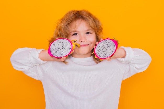 Kids face with fruits Kid hold dragon fruit in studio Studio portrait of cute child with dragon fruit isolated on yellow background