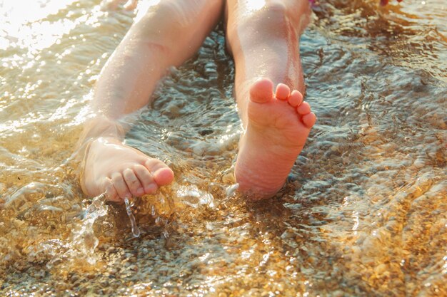 Kids feet on the beach in the water