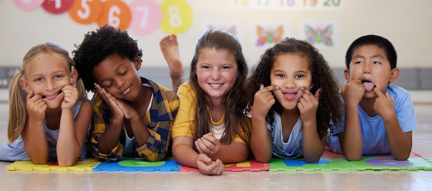 Photo kids floor and group portrait with funny face in school classroom solidarity or diversity in childhood girl boy and children in class academy and happy multicultural friends together or playful