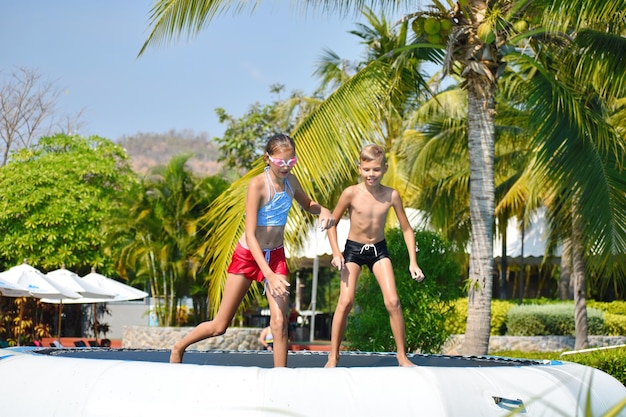 Kids fun jumping on trampoline Children jump into water Happy summer time in Park