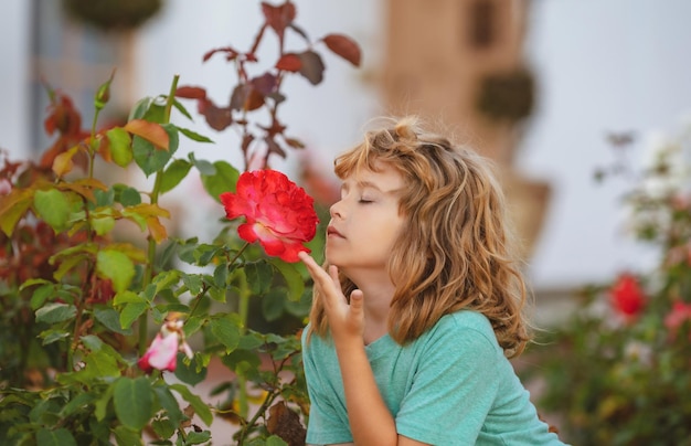 Kids funny face boy with flowers child smelling rose in yard