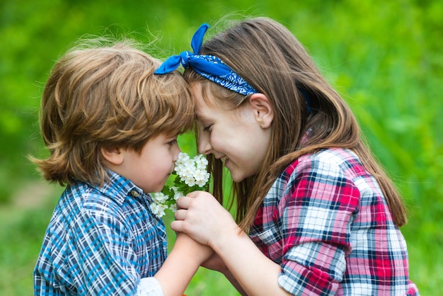 Kids girl and boy blowing dandelion flower in green meadow outdoor