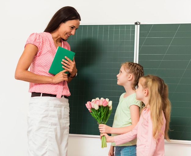 Photo kids giving flowers to their teacher