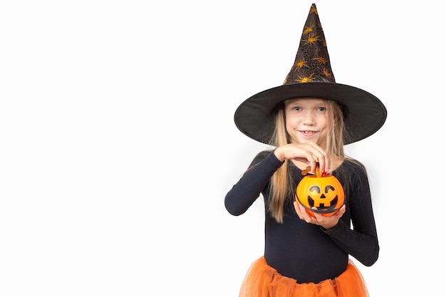 Kids Halloween A beautiful cute girl in a witch costume wearing a hat takes out candy from a basket