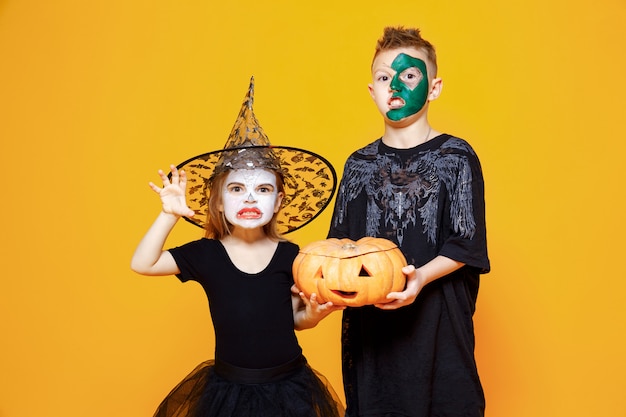 Kids in halloween costumes holding a pumpkin