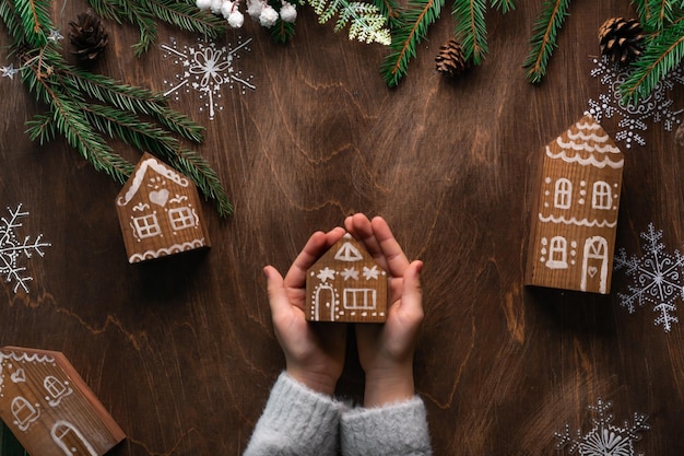 Mani dei bambini che tengono la casa di pan di zenzero di natale regalo di natale fatto a mano vista dall'alto