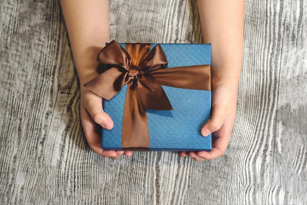 Kids hands holding a gift on the wooden background