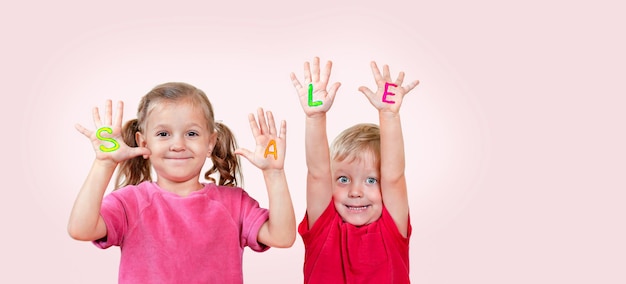 Foto i bambini annunciano felicemente la stagione dei saldi scrivendo lettere sui palmi delle mani