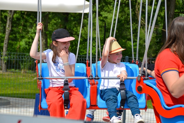 Photo kids having fun in ferris wheel with chains carousel ski flyer in amusement park