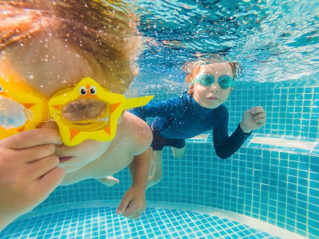 Kids having fun playing underwater in swimming pool on summer vacation