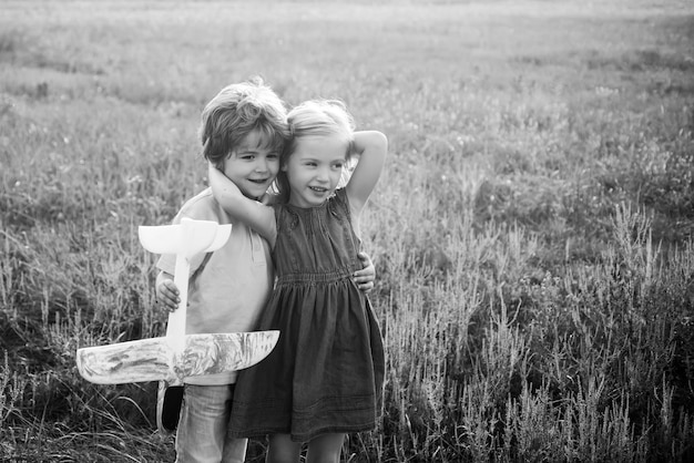 Kids having fun with toy airplane in field against nature background Childhood concept Happy childho