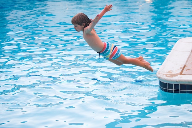Дети прыгают в бассейн Счастливый ребенок плавает в бассейне