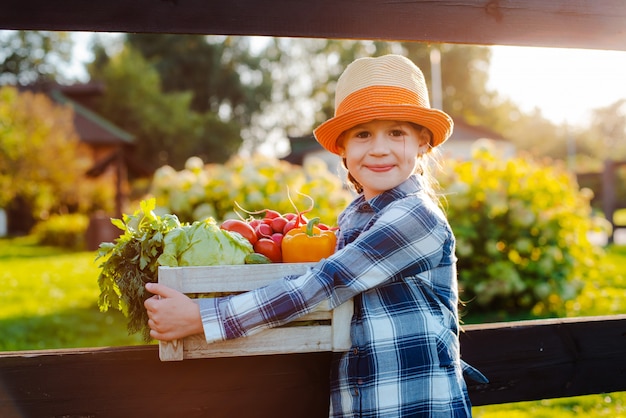 Kids little girl holding a basket of fresh organic vegetables