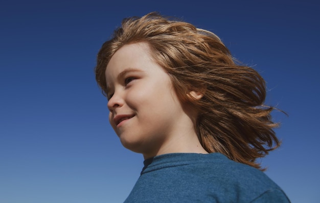 Kids looking away close up head of cute child on blue sky with copy space