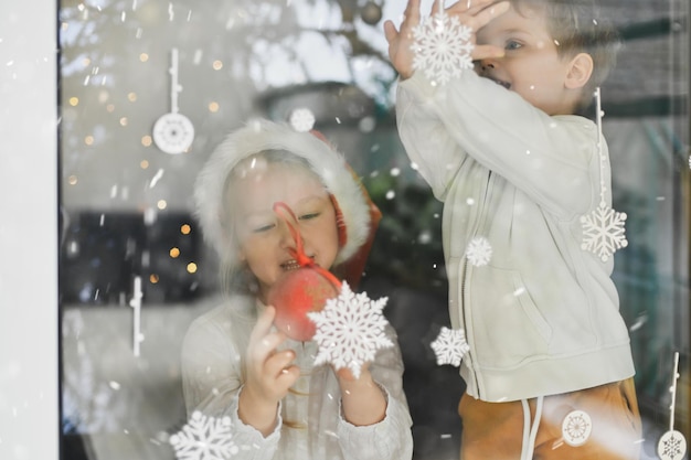 窓の雪片を見ている子供たち