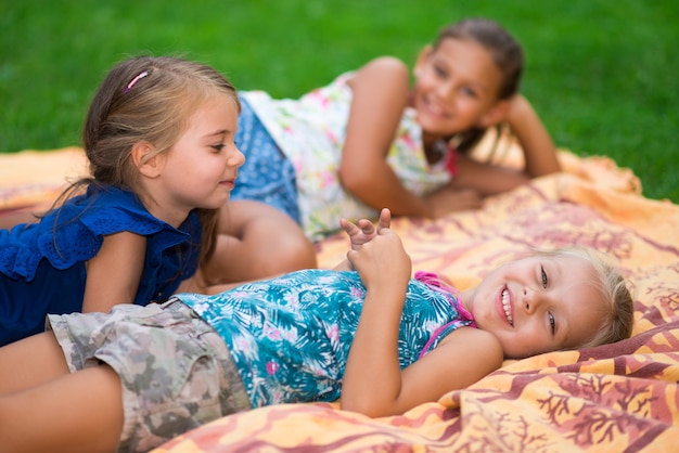 Kids lying on a blanket in a grass field