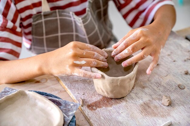 写真 湿った粘土から陶器のカップを作る子供たち