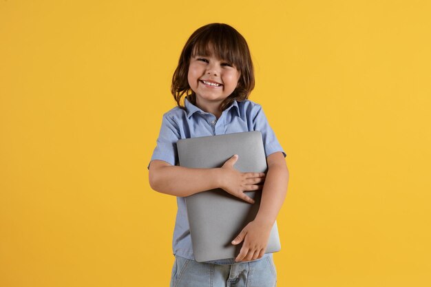 Kids and modern technologies studio portrait of adorable little boy carrying laptop in hands and smiling to camera