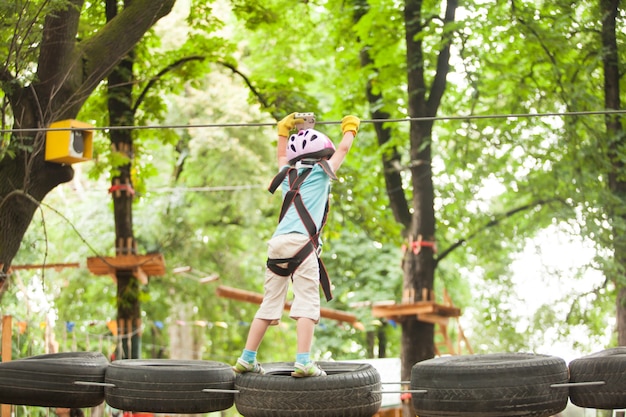 Kids on obstacle course in adventure park in mountain helmet and safety equipment