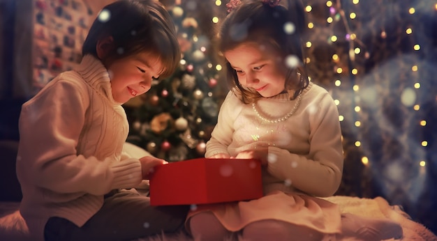 Kids opening Xmas presents Children under Christmas tree with gift boxes