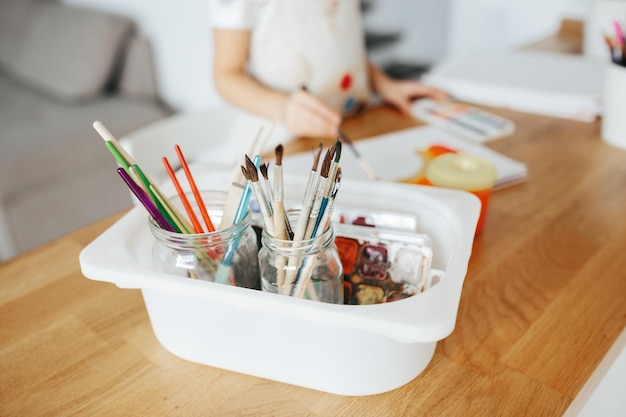 Kids painting watercolor rainbows at table at home