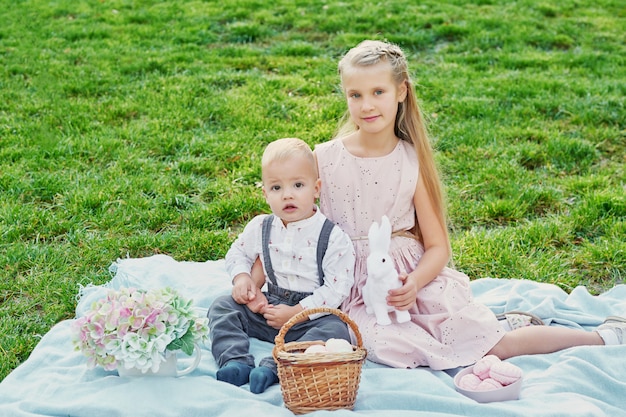 Bambini nel parco il picnic di pasqua con uova e coniglio