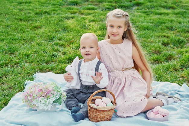 Bambini nel parco il picnic di pasqua con uova e coniglio