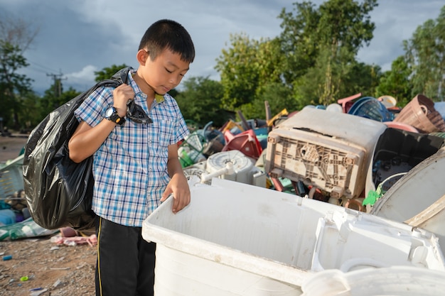 子供たちはプラスチックの山に黒い袋にゴミを拾います