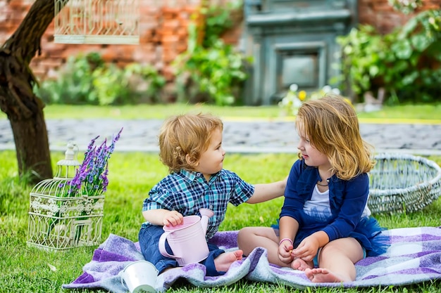 Kids at picnic. Happy child in park. Sister feeding baby boy. Girl feeds brother with a spoon. Kid food.