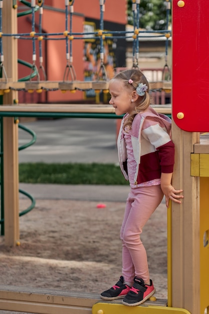 子供たちは遊び場で遊ぶ。幸せな笑いの女の子は、スイングや登山を楽しんでいます。野外活動