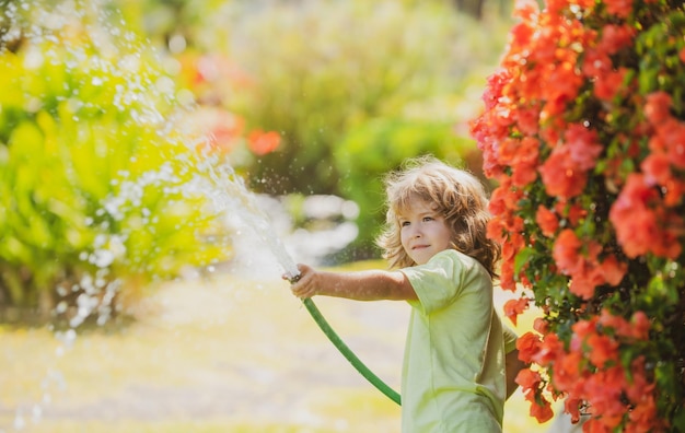 子供たちは庭で水庭のホースで遊ぶ屋外の子供たちの夏の楽しみ水で遊ぶ小さな男の子h