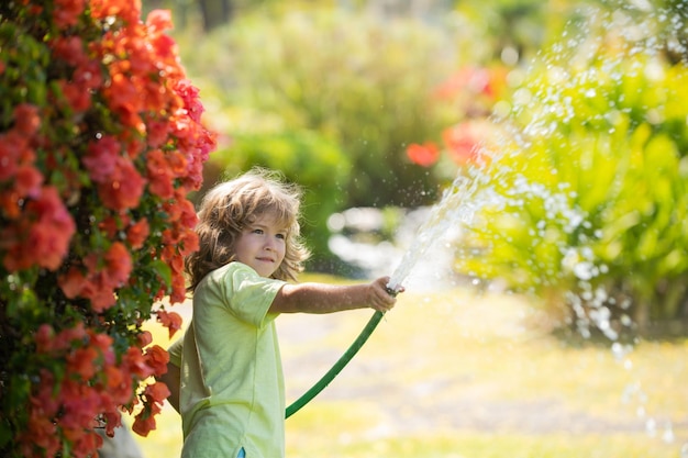 Kids play with water garden hose in yard. Outdoor children summer fun. Little boy playing with water hose in backyard. Party game for children. Healthy activity for hot sunny day.