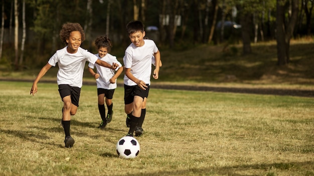 Kids playing football supervised by football trainer