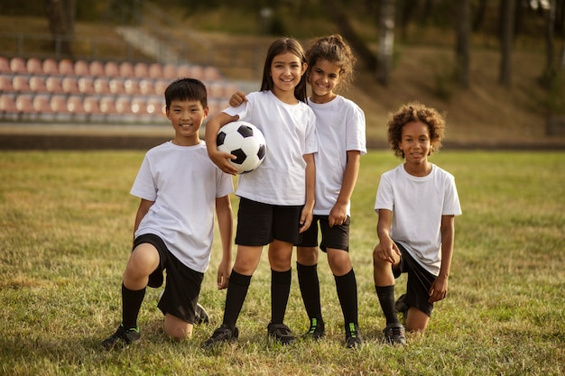 Kids playing football supervised by football trainer