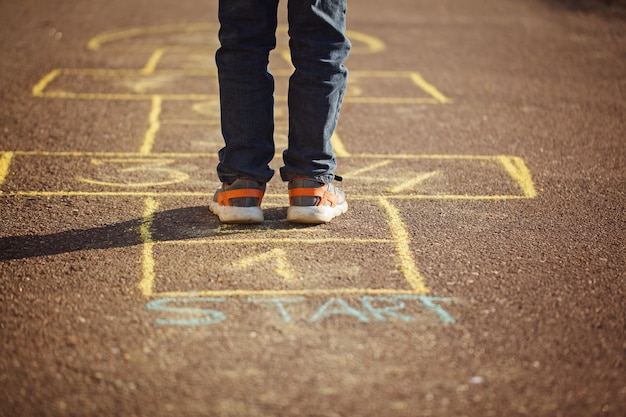 Kids playing hopscotch on playground outdoors. Hopscotch popular street game