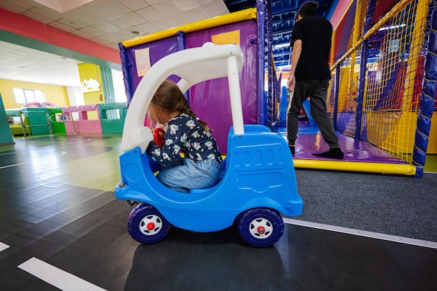 Kids playing at indoor play center playground girl in toy car